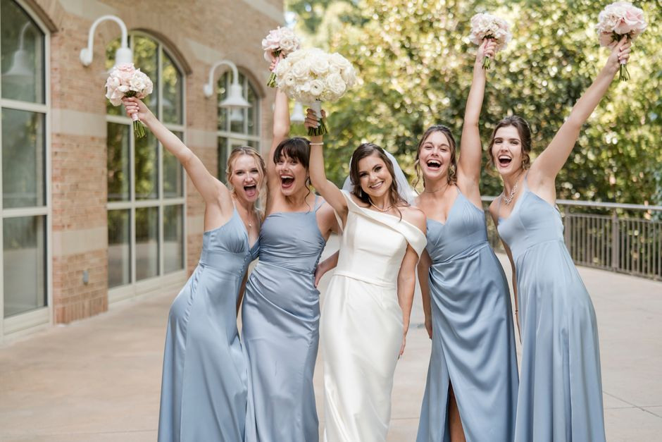 Happy smiling bride and bridesmaids raising their bouquets
